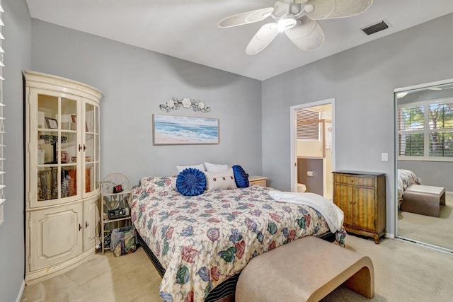 bedroom featuring visible vents, light colored carpet, ensuite bath, and ceiling fan