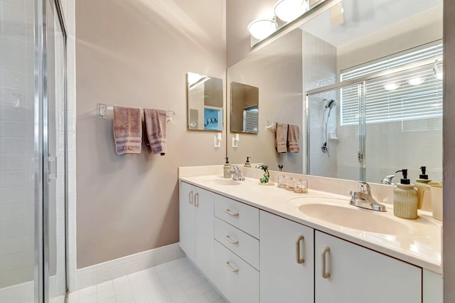 full bath featuring a sink, baseboards, a stall shower, and double vanity