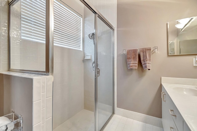 bathroom with baseboards, vanity, a shower stall, and tile patterned flooring