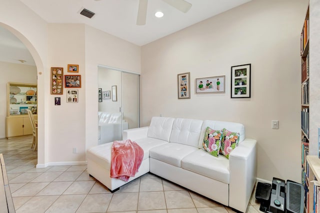 living room with light tile patterned floors, baseboards, visible vents, arched walkways, and ceiling fan