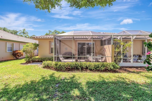 rear view of property featuring stucco siding, a yard, glass enclosure, and a tile roof