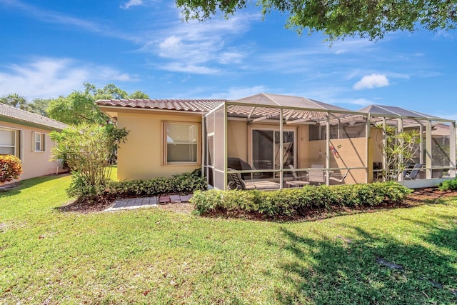 back of house featuring a lanai, stucco siding, a tiled roof, and a lawn