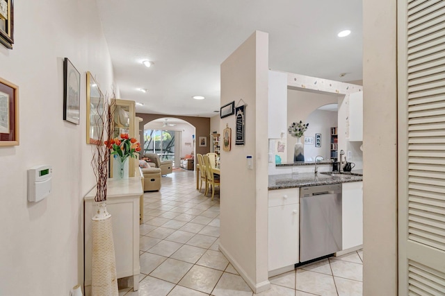 interior space with light tile patterned floors, arched walkways, and stainless steel dishwasher