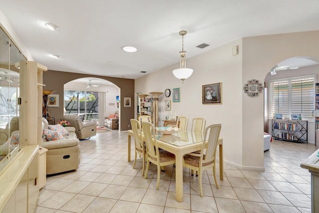 dining area with arched walkways, light tile patterned floors, a ceiling fan, and visible vents