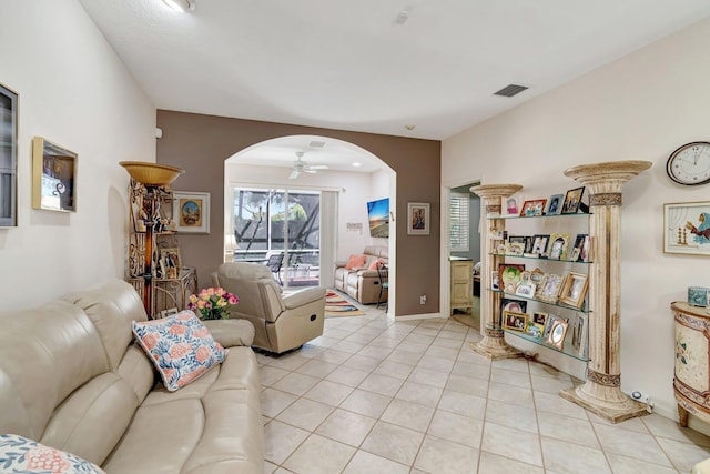 living room featuring visible vents, arched walkways, light tile patterned flooring, baseboards, and ceiling fan