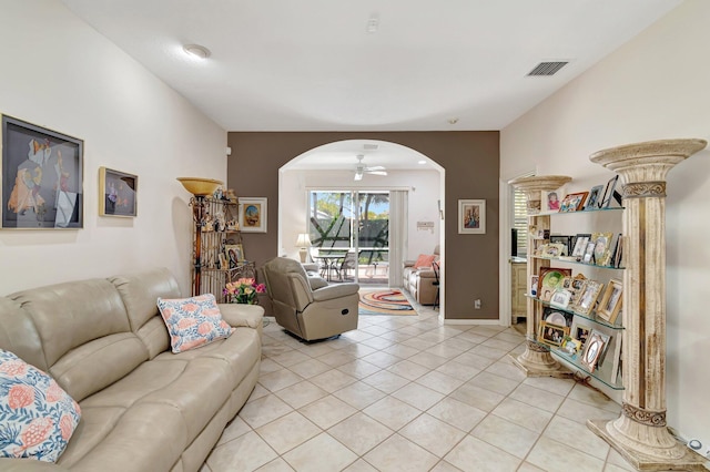 living area featuring visible vents, baseboards, light tile patterned flooring, arched walkways, and a ceiling fan
