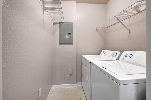 washroom featuring laundry area, electric panel, baseboards, a textured wall, and washer and dryer