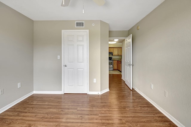 unfurnished bedroom with a ceiling fan, wood finished floors, visible vents, and baseboards