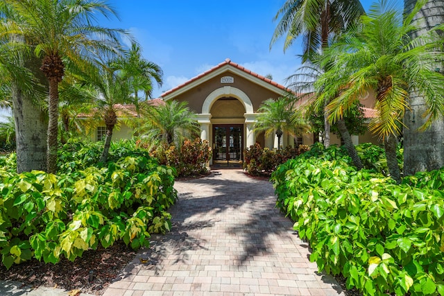 doorway to property with french doors, a tile roof, and stucco siding