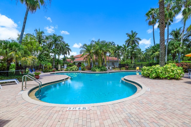 community pool with a patio area and fence