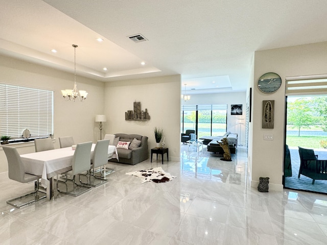 living room with a tray ceiling, a wealth of natural light, and a chandelier