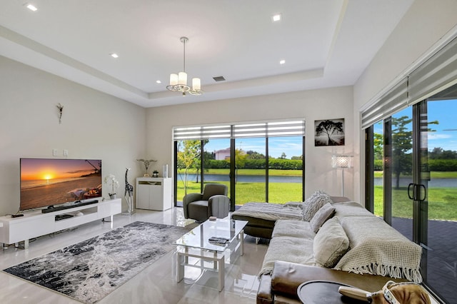 living room featuring a chandelier, a raised ceiling, and a healthy amount of sunlight