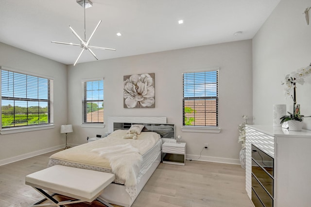 bedroom featuring ceiling fan with notable chandelier and light hardwood / wood-style flooring