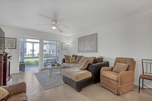 living area with light tile patterned flooring, a ceiling fan, and baseboards