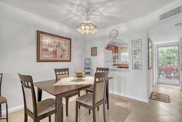 dining space with light tile patterned floors, baseboards, visible vents, and arched walkways