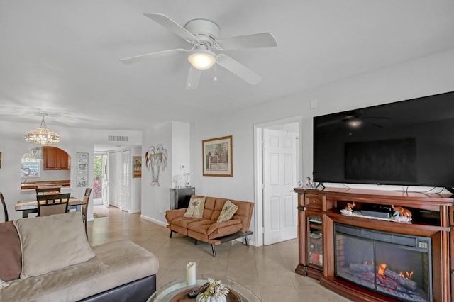 living area featuring light tile patterned flooring, visible vents, baseboards, a ceiling fan, and a lit fireplace