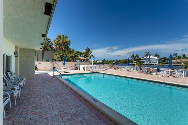 community pool with a patio area and fence