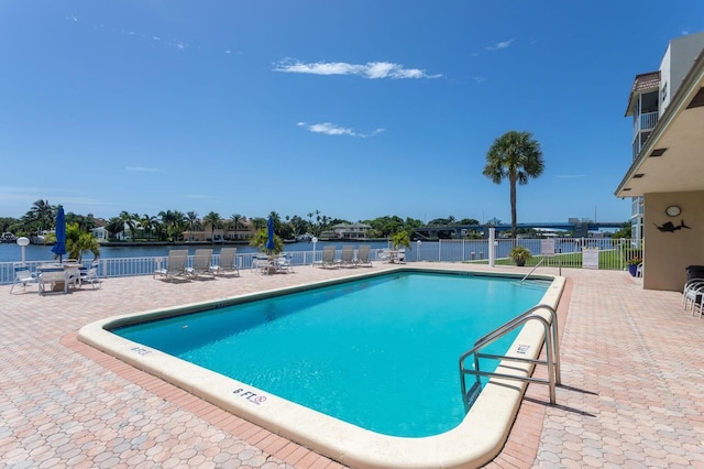 community pool featuring a water view, fence, and a patio