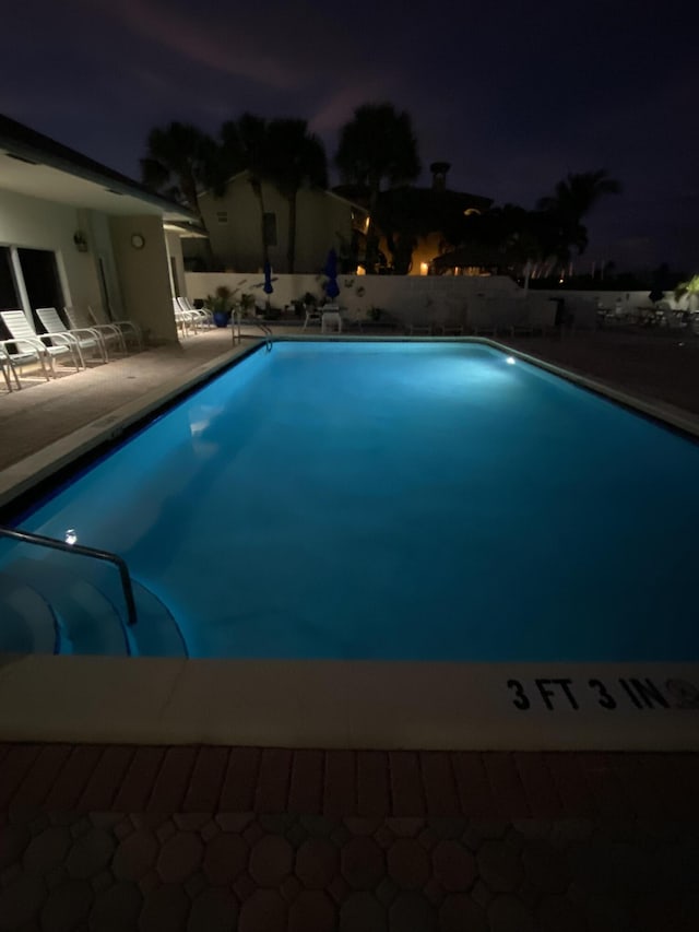 pool at twilight with a fenced in pool and a patio