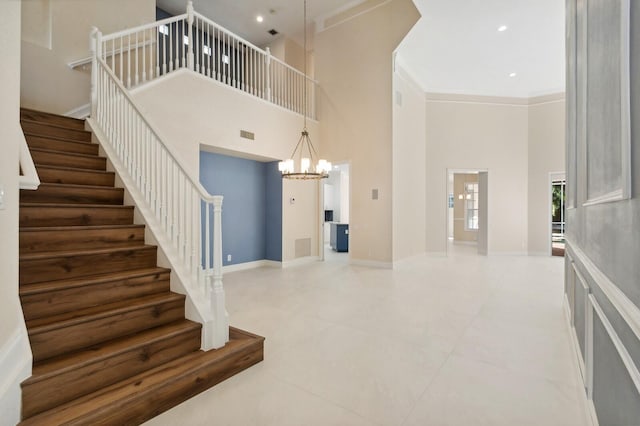 staircase with crown molding, a high ceiling, a notable chandelier, and tile patterned flooring