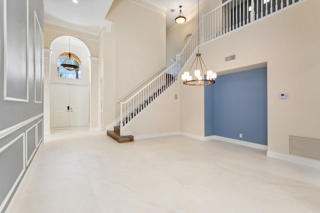 tiled entrance foyer featuring a high ceiling, crown molding, and an inviting chandelier