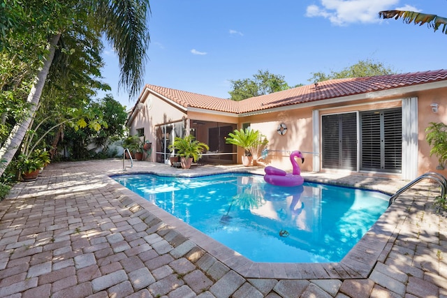 view of pool with a sunroom and a patio area