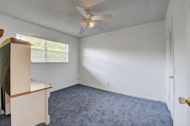 spare room with ceiling fan, dark carpet, and a textured ceiling