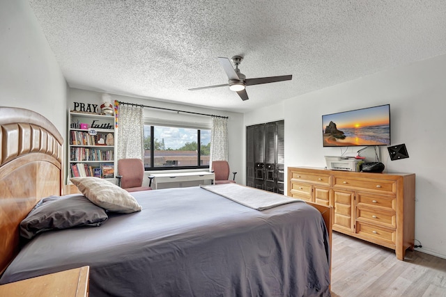 bedroom with ceiling fan, a textured ceiling, and light hardwood / wood-style flooring