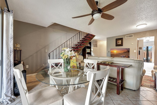 tiled dining space featuring a textured ceiling and ceiling fan