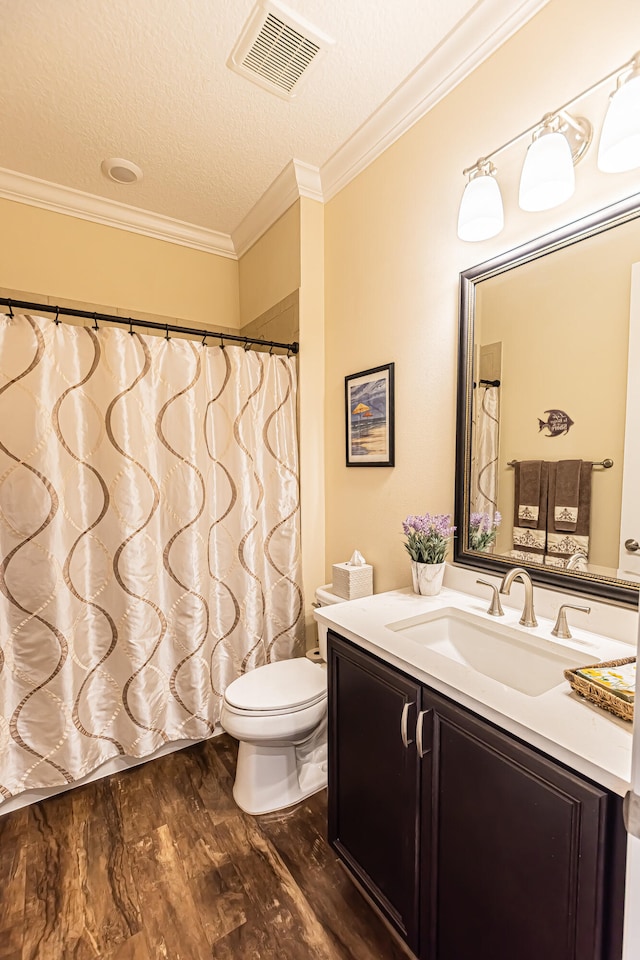 bathroom with a textured ceiling, hardwood / wood-style floors, toilet, vanity, and ornamental molding