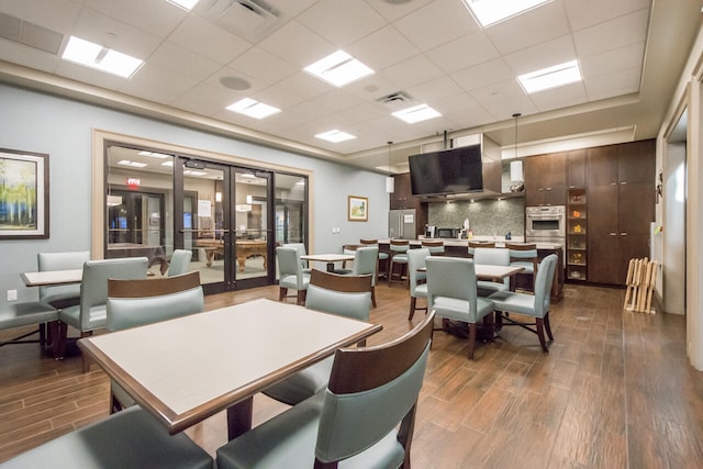 dining area with a paneled ceiling, hardwood / wood-style flooring, and french doors