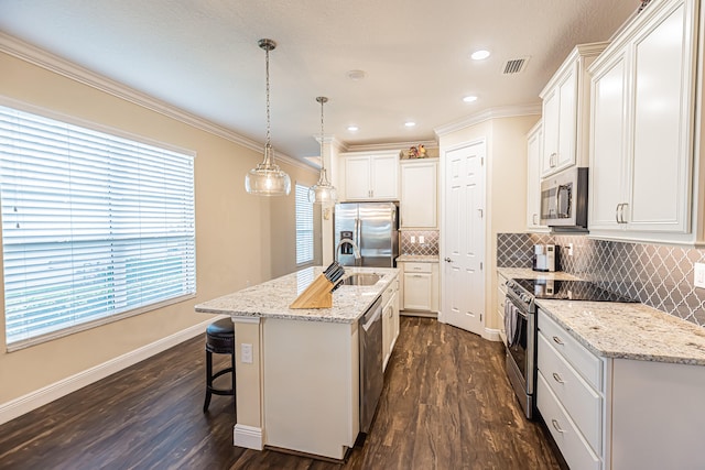 kitchen with an island with sink, dark hardwood / wood-style floors, appliances with stainless steel finishes, and decorative backsplash