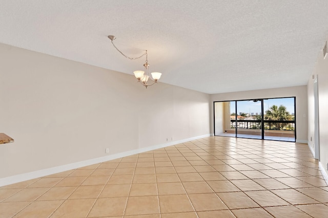 unfurnished room with light tile patterned flooring, a textured ceiling, and a notable chandelier