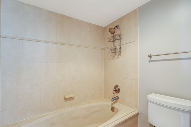 bathroom featuring tiled shower / bath combo and toilet