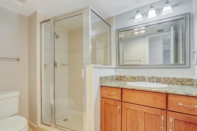 bathroom featuring a shower with shower door, toilet, and vanity