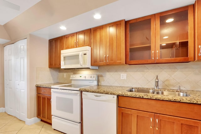 kitchen with light tile patterned flooring, decorative backsplash, white appliances, sink, and light stone counters