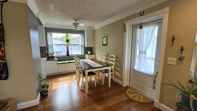 dining space with hardwood / wood-style flooring, a textured ceiling, ornamental molding, and ceiling fan