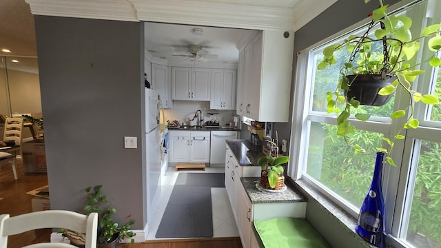 kitchen with ceiling fan, decorative backsplash, sink, white dishwasher, and white cabinets