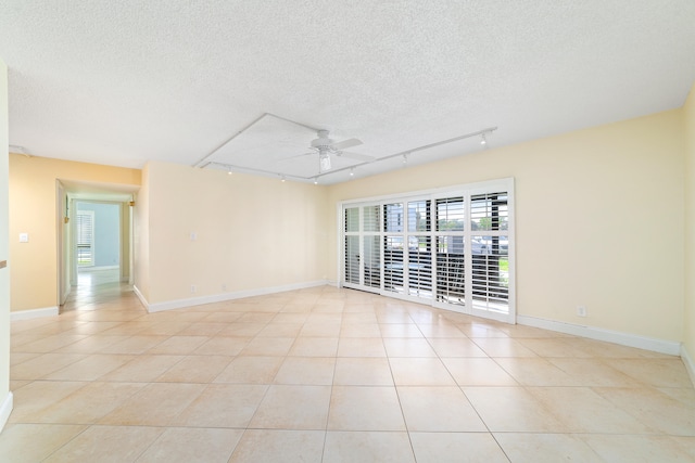 unfurnished room with a textured ceiling, rail lighting, light tile patterned floors, and ceiling fan