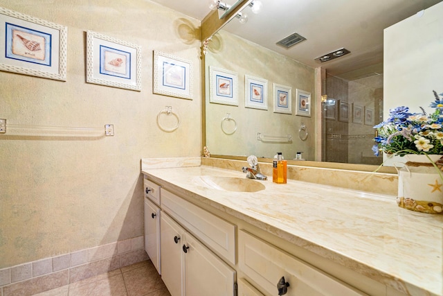 bathroom featuring tile patterned floors, vanity, and a tile shower