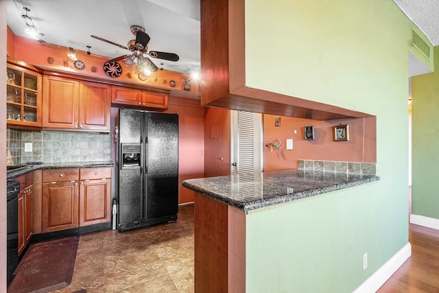 kitchen with backsplash, ceiling fan, dark stone countertops, black fridge with ice dispenser, and kitchen peninsula