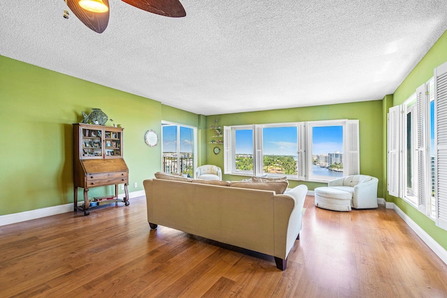 living room featuring a textured ceiling, hardwood / wood-style flooring, and ceiling fan