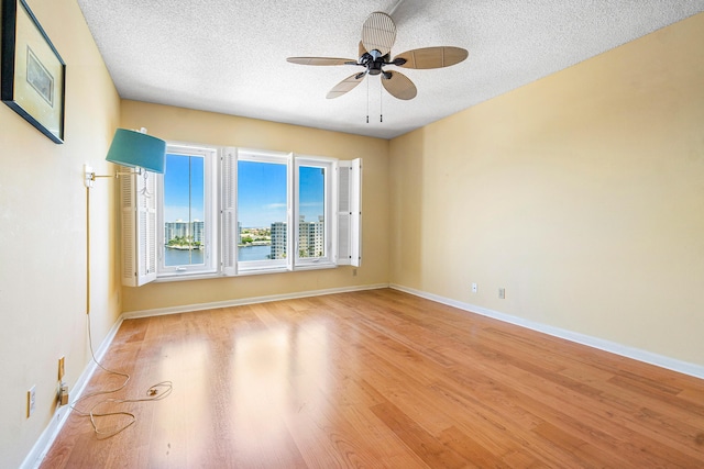 spare room featuring ceiling fan, light hardwood / wood-style floors, and a textured ceiling