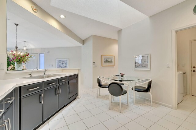 kitchen featuring pendant lighting, sink, light tile patterned floors, dishwasher, and washer / dryer