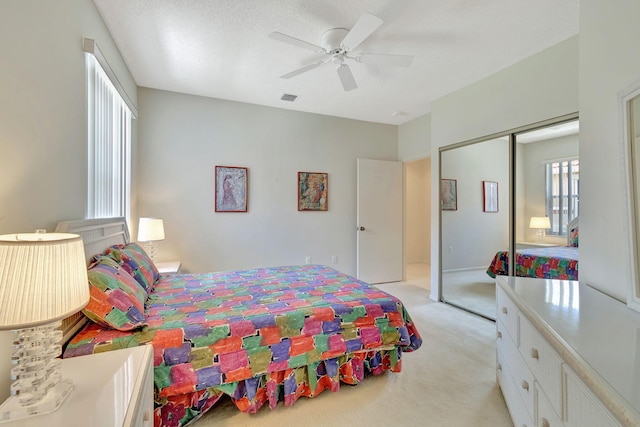 carpeted bedroom with a textured ceiling, ceiling fan, and a closet