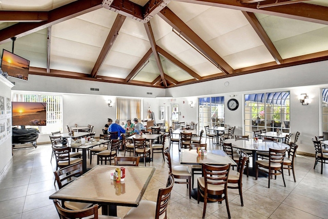 tiled dining area featuring beam ceiling and high vaulted ceiling