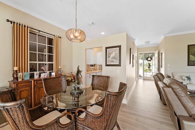 dining space with light wood-type flooring, a notable chandelier, and ornamental molding