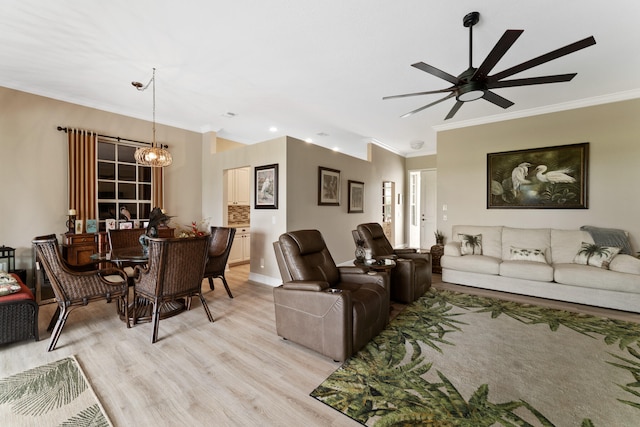 living room featuring light hardwood / wood-style flooring, ornamental molding, and ceiling fan with notable chandelier