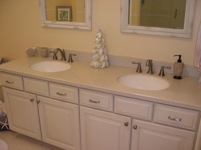 bathroom featuring an enclosed shower, a sink, and double vanity