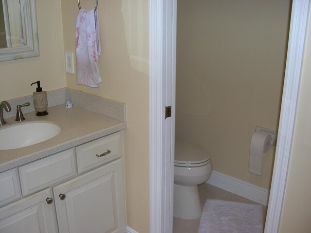 bathroom featuring baseboards, vanity, tile patterned flooring, and toilet